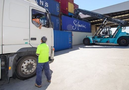 Tasman Logistics - supervisor talking to driver with reach stacker in bkgd